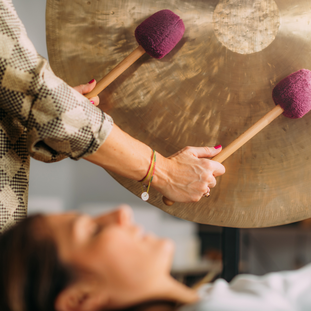 A person laying on the ground with a gong in front of them.